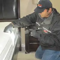 Bed bug inspection technician checking a mattress and bed frame for signs of infestation in San Jose, CA