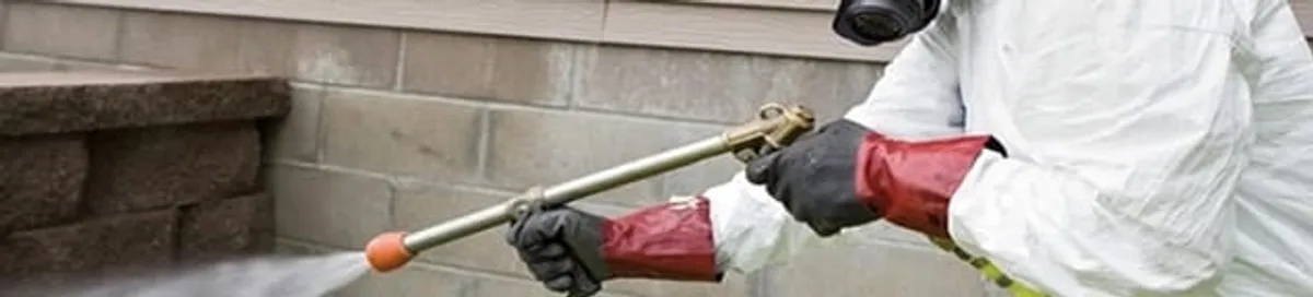 Pest control technician applying exterior insect treatment along a home foundation in San Jose, CA