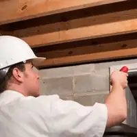 Termite inspection technician checking a basement wall and framing for termite activity in San Jose, CA